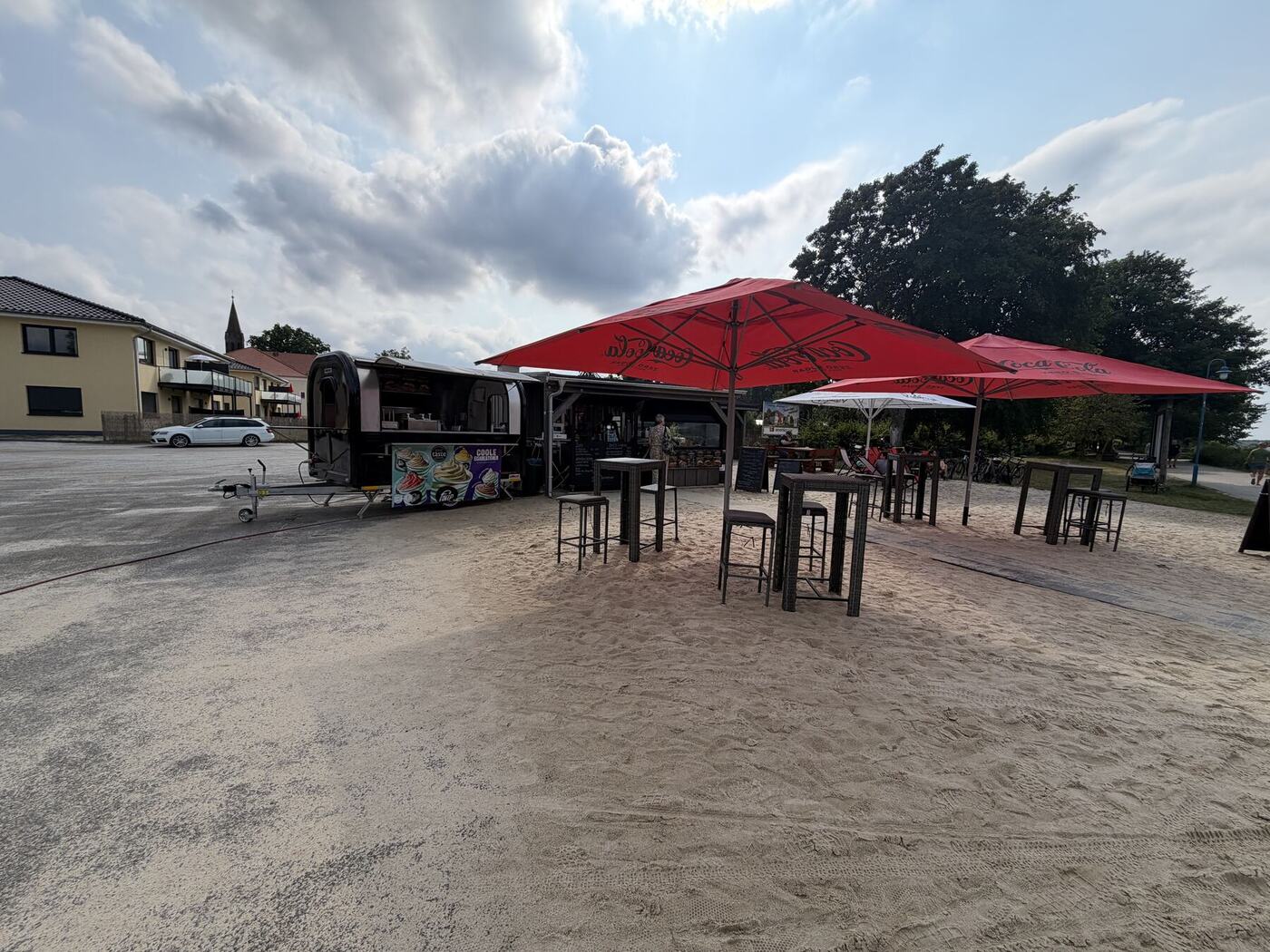 Ufer Grill mit roten Schirmen im Sand an der Promenade